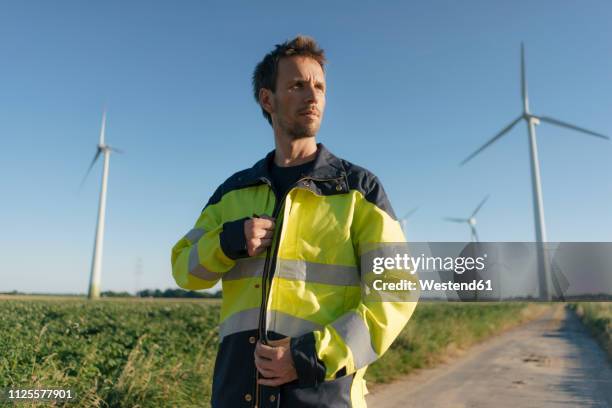 portrait of an engineer on field path at a wind farm - man jacket stock pictures, royalty-free photos & images