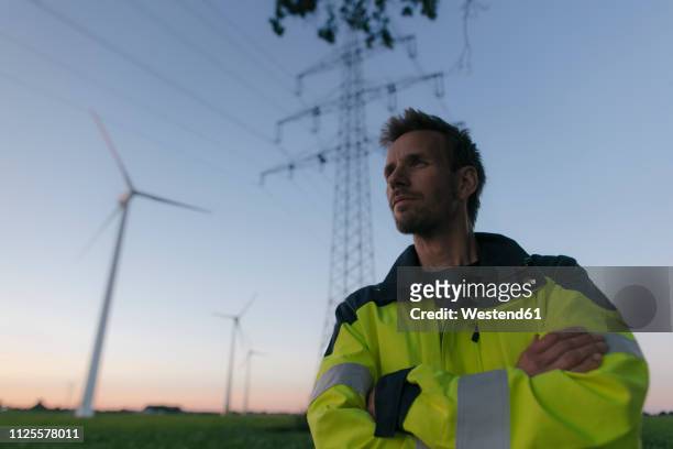 portrait of an engineer next to a wind farm and power pole - electricity pylon 個照片及圖片檔