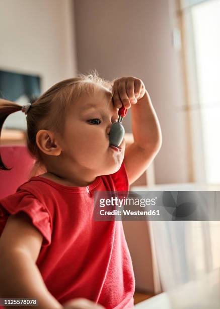 portrait of little girl playing with plasic spoon - baby eating toy foto e immagini stock