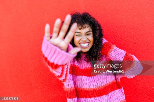 portrait of laughing young woman in front of red wall - alleen jonge vrouwen stockfoto's en -beelden