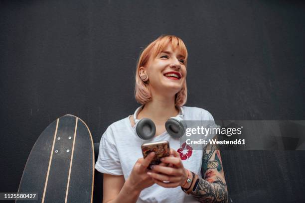 happy young woman with skateboard, headphones and cell phone - character stock photos et images de collection