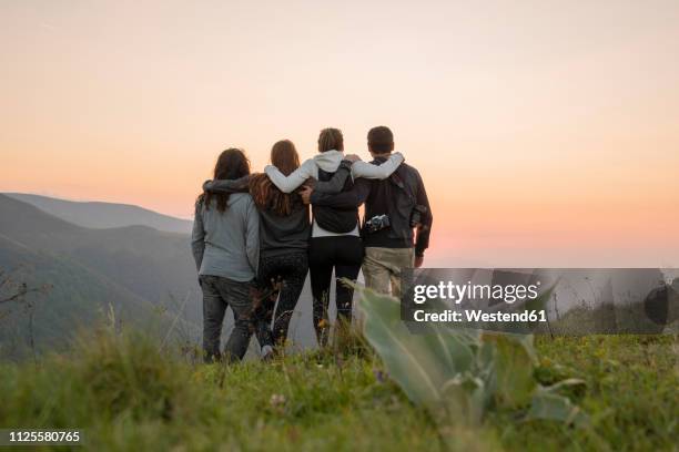 bulgaria, balkan mountains, group of hikers standing on viewpoint at sunset - arm in arm stockfoto's en -beelden