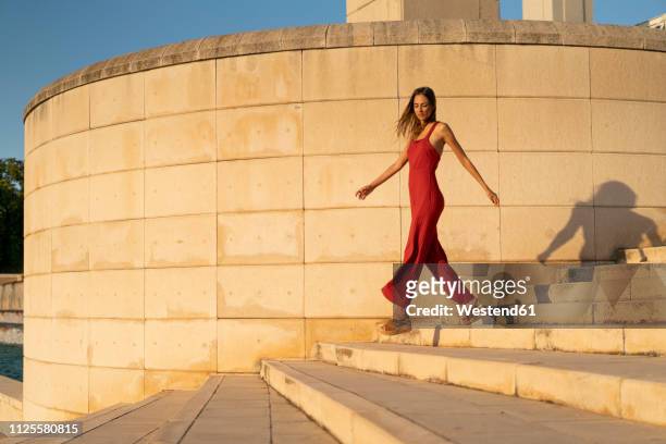 spain, barcelona, montjuic, young woman wearing red jumpsuit walking on stairs - jumpsuit fashion stock pictures, royalty-free photos & images