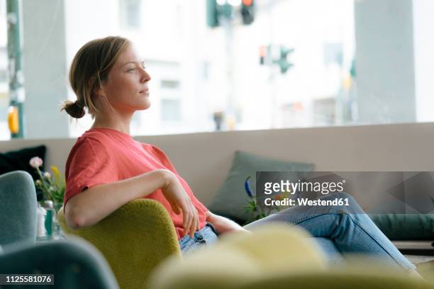 young woman sitting in a cafe - casual woman pensive side view stockfoto's en -beelden