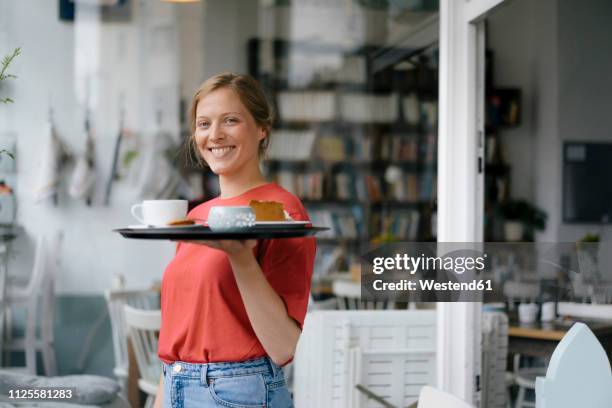 portrait of smiling young woman serving coffee and cake in a cafe - food service occupation stock-fotos und bilder