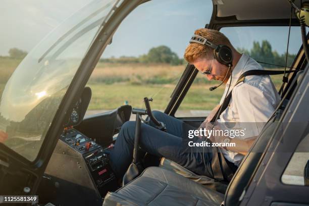 helicopter pilot fastening seat belt in cockpit - fasten stock pictures, royalty-free photos & images