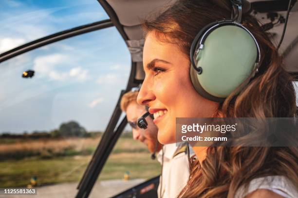 female passenger with headset in helicopter cockpit sitting by the pilot - helicopter cockpit stock pictures, royalty-free photos & images