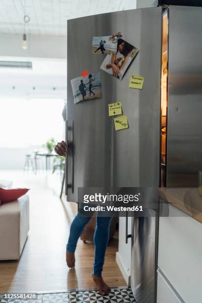 hungry woman standing in kitchen, searching her fridge - refrigerator stock-fotos und bilder