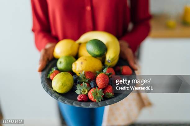woman holding plate with fruit - fruit bowl stock pictures, royalty-free photos & images