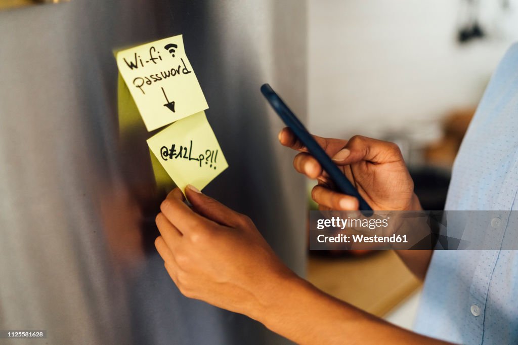 Woman in her kitchen in the morning, posting sticky notes on the fridge