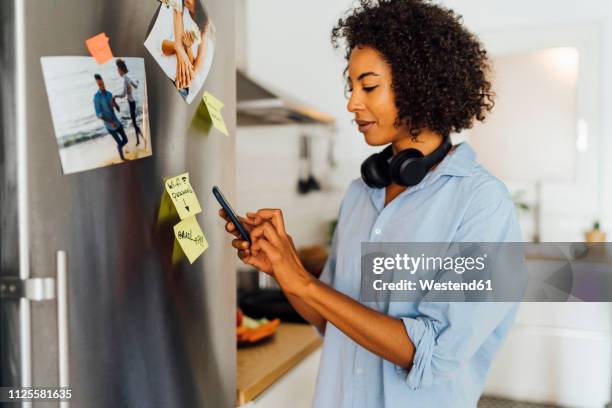 woman in her kitchen in the morning, posting sticky  notes on the fridge - sticky note pad stock pictures, royalty-free photos & images