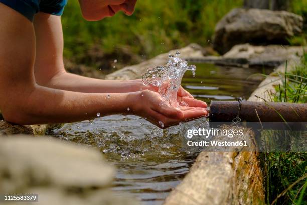 germany, upper bavaria, chiemgau, young man refreshing at a fountain - hands fountain water stock-fotos und bilder