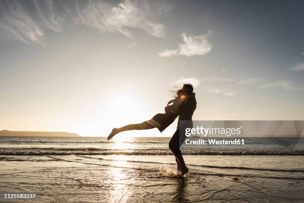 france, brittany, happy young couple hugging on the beach at sunset - sun flare couple stock pictures, royalty-free photos & images