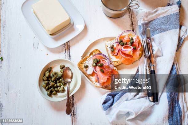 slices of toast with smoked salmon, caperberries, onion rings, and coffee - kapris bildbanksfoton och bilder