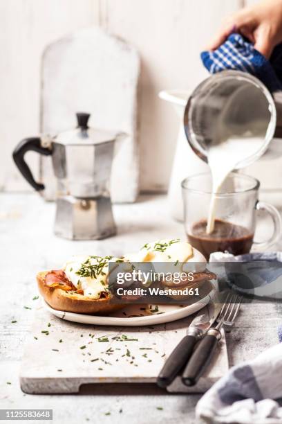 traditional egg benedict with slices of bacon on toast,  poached egg and hollandaise - eggs benedict stock pictures, royalty-free photos & images