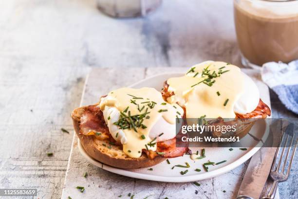 traditional egg benedict with slices of bacon on toast,  poached egg and hollandaise - eggs benedict stock pictures, royalty-free photos & images