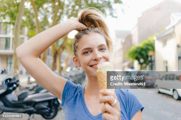 netherlands, maastricht, portrait of happy blond young woman holding ice cream cone in the city - woman ice cream stock pictures, royalty-free photos & images