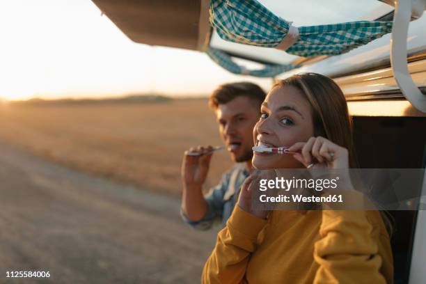 couple brushing teeth at camper van in rural landscape at sunset - brushing teeth stock pictures, royalty-free photos & images