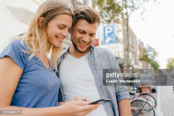 netherlands, maastricht, happy young couple looking at cell phone the city - limburgo países bajos fotografías e imágenes de stock