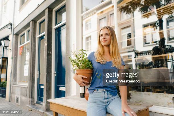 netherlands, maastricht, blond young woman holding flowerpot in the city - years of the kingdom of the netherlands in maastricht stockfoto's en -beelden