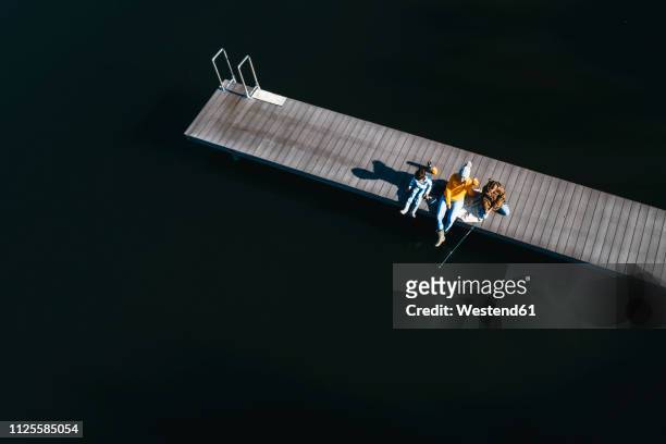 family sitting on jetty, fishing in autunm - boardwalk stockfoto's en -beelden