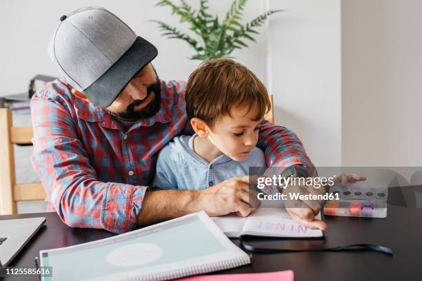 father texplaining his son the smartwatch, while working at home - computador utilizável como acessório imagens e fotografias de stock