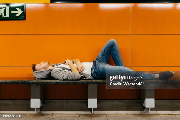 young man waiting for the metro, resting on bench - subway bench bildbanksfoton och bilder