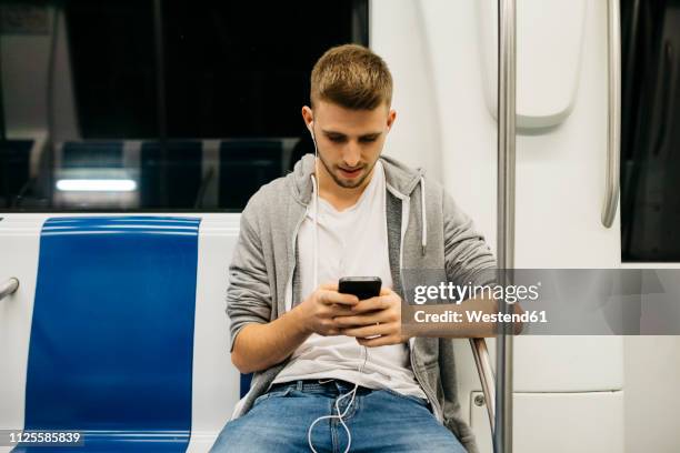 young man using smartphone in metro - u bahnzug stock-fotos und bilder