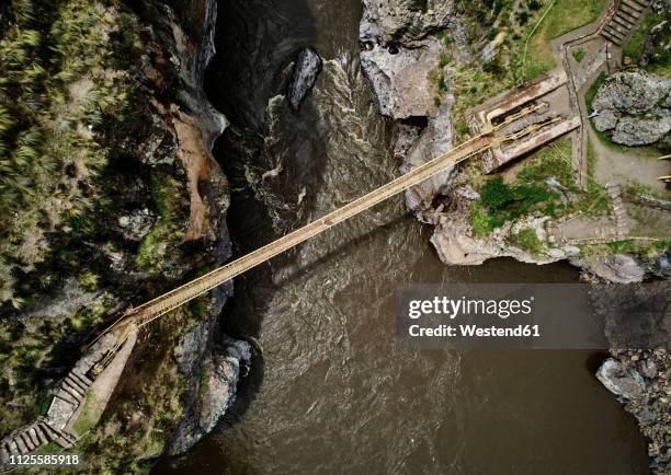 peru, quehue, aerial view of woman crossing rope bridge - touwbrug stockfoto's en -beelden