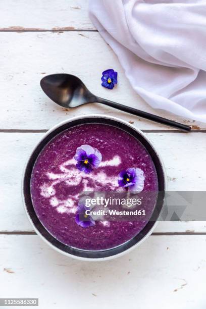 bowl of creamed red cabbage soup garnished with edible flowers - cabbage flower stock-fotos und bilder