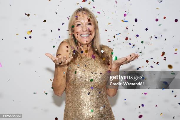 senior woman wearing golden dress, celebtraing new year's eve - a 61 year old woman stock pictures, royalty-free photos & images