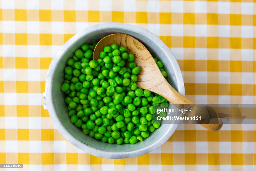 Peas in bowl, wooden spoon from above