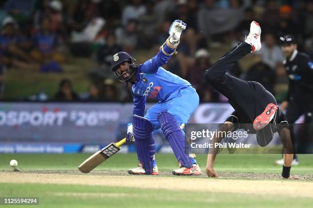 Trent Boult of New Zealand takes a dive as Dinesh Karthik of India looks on during game three of the One Day International series between New Zealand...