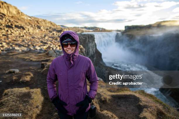 happy tourist against dettifoss waterfall background - dettifoss falls stock pictures, royalty-free photos & images