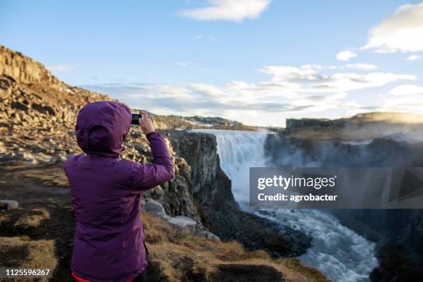 turista felice contro lo sfondo della cascata di dettifoss - dettifoss waterfall foto e immagini stock