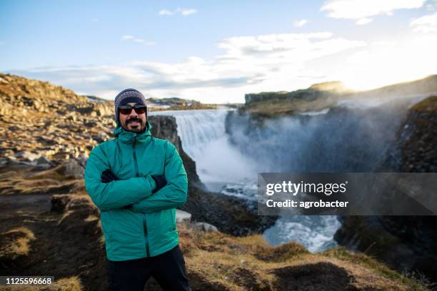 happy tourist against dettifoss waterfall background - dettifoss falls stock pictures, royalty-free photos & images