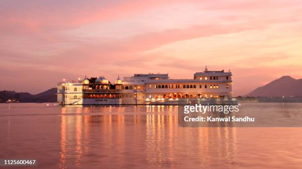 sunset view of taj lake palace floating on lake pichola - palace stock pictures, royalty-free photos & images