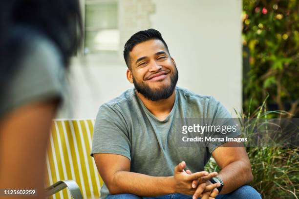 young man smiling in yard during social gathering - tevreden stockfoto's en -beelden