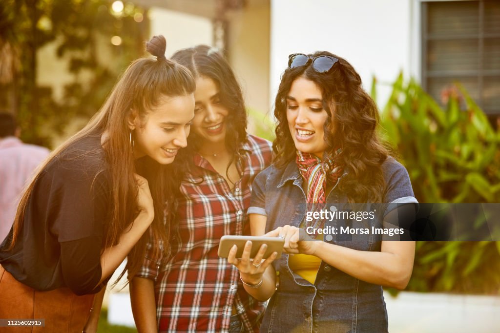 Friends Looking Friends Looking At Photos On Mobile Phone In Party High-Res Stock Photo ...