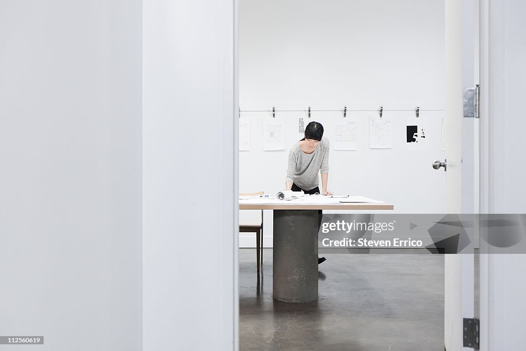 Woman looking at architectural plans in office