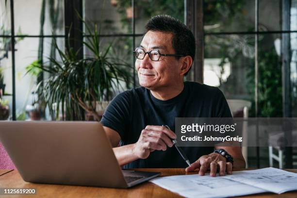 volwassen chinese man met laptop thuis - male looking content stockfoto's en -beelden