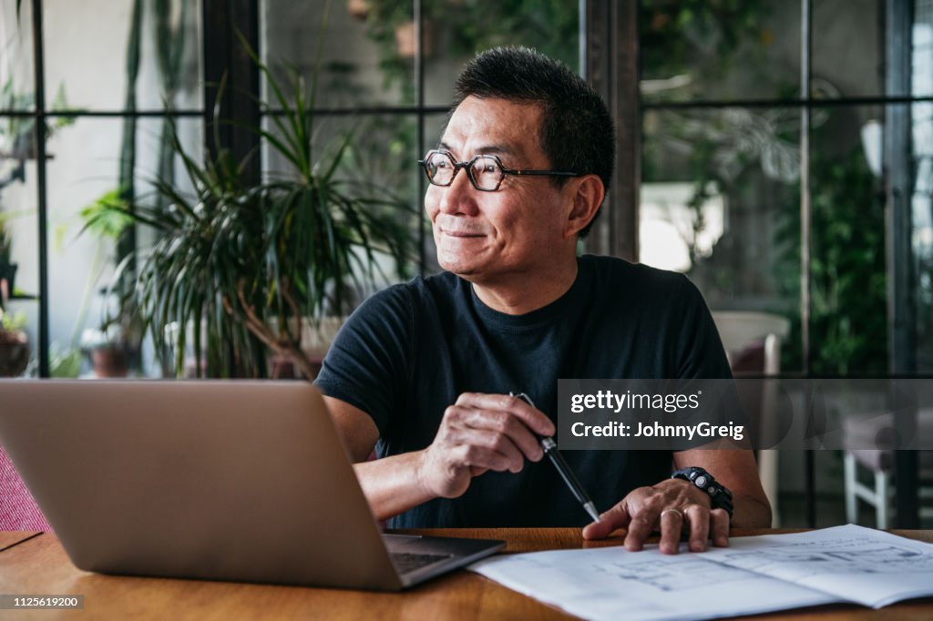 Mature Chinese man using laptop at home