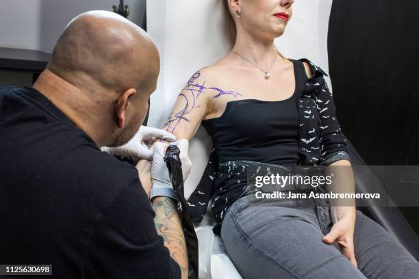 woman is having tattoo done on her arm by tattoo artist - beautiful czech women 個照片及圖片檔