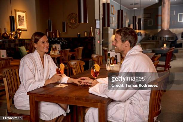 affectionate couple in bathrobes having a drink in a spa restaurant - robe 2017 stock pictures, royalty-free photos & images