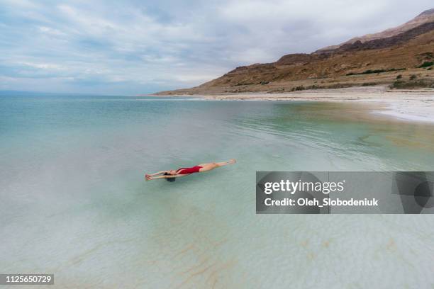 frau schwimmt auf wasser im toten meer - jordanian stock-fotos und bilder