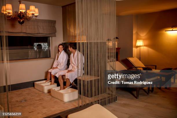 couple in bathrobes taking a footbath in a spa - sauna wellness stock pictures, royalty-free photos & images