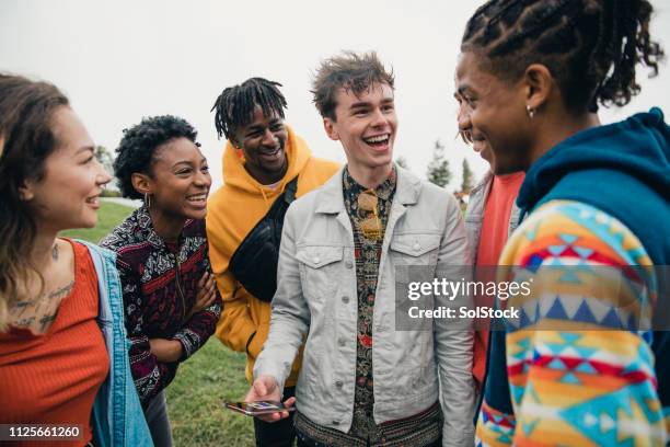 sharing socials in the park - teens hanging out outside stock pictures, royalty-free photos & images