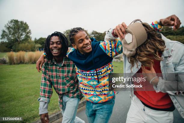 junge männer hanging out im park - british culture walking stock-fotos und bilder