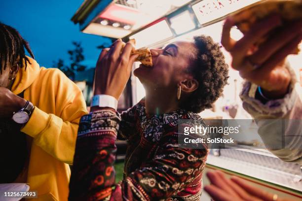young woman eating pizza at festival - music festival stock pictures, royalty-free photos & images