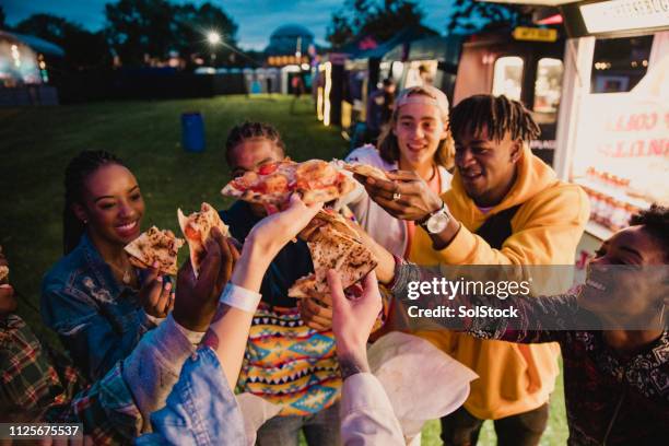 festival goers sharing pizza - booth university college stock pictures, royalty-free photos & images